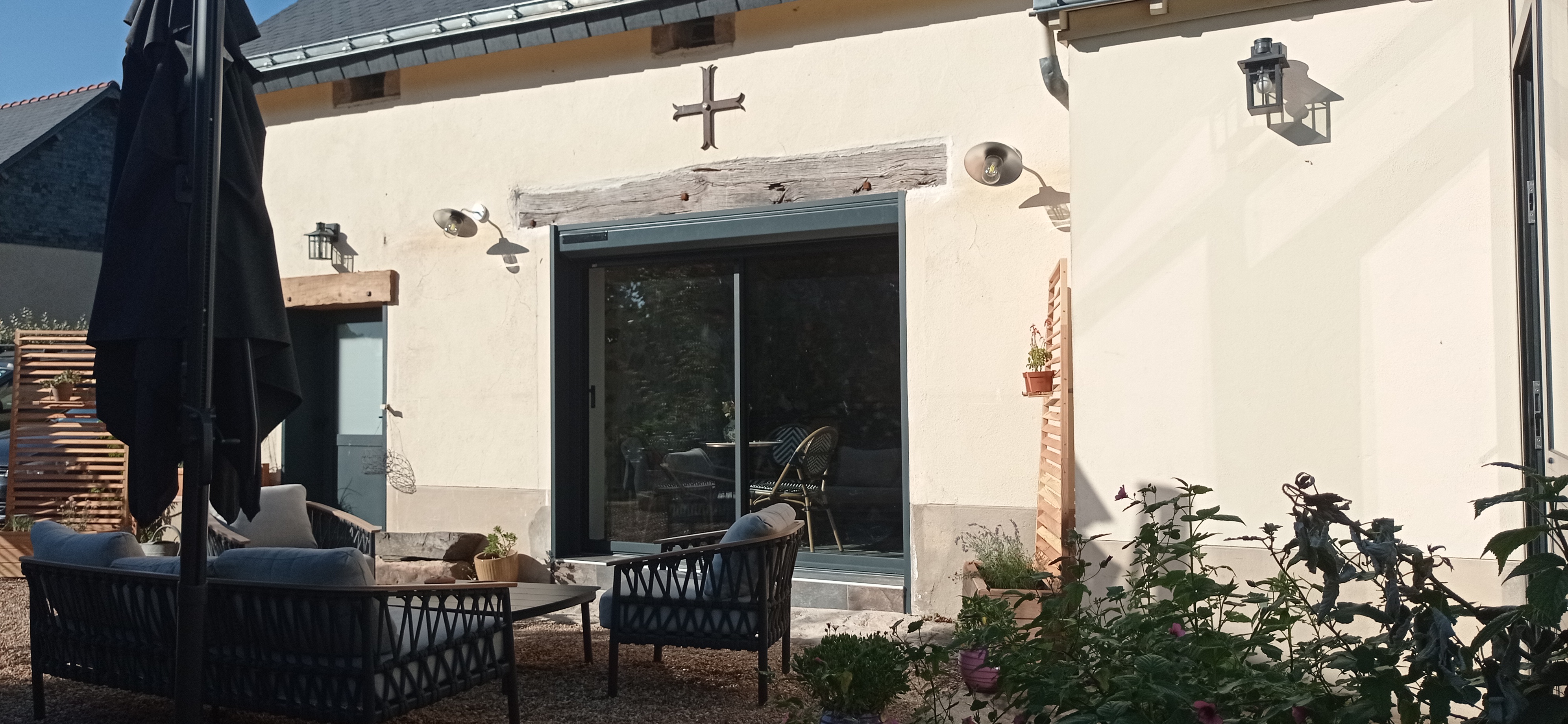 Vue sur le jardin fleuri et la façade en pierre du gîte